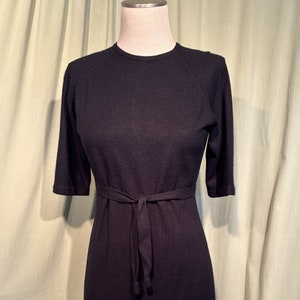 May include: A black, knee-length, knitted dress with a self-tie belt.