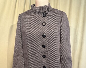 May include: A gray and white striped coat with a high collar and a row of black buttons down the front.
