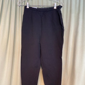 May include: Black trousers with a high waist and elastic straps at the bottom of the legs.