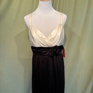 Peut inclure: Une robe sans manches blanche et noire avec une ceinture en satin noir et une fleur noire en embellissement.