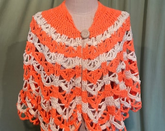 May include: A crocheted shawl in orange and white with a button closure. The shawl is made with a lacy stitch and has a scalloped edge.