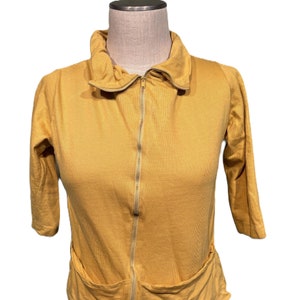 May include: A mustard yellow zip-up sweater with a high collar and two pockets.