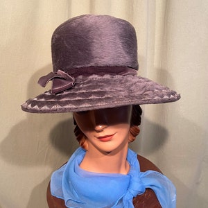 May include: A gray felt hat with a wide brim and a velvet ribbon. The hat is trimmed with a velvet bow.