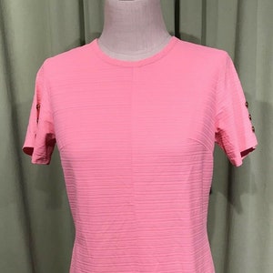 May include: A pink short-sleeved dress with a vertical seam down the front and gold buttons on the right side.