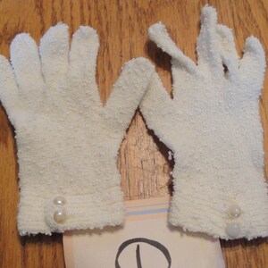 May include: A pair of white terrycloth gloves with pearl embellishments on the cuffs.