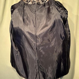 May include: A black jacket with a gold and black floral pattern on the collar and hem.