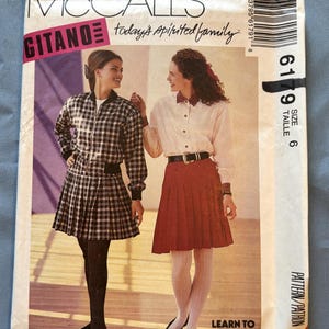 May include: A sewing pattern for a plaid skirt and a white button-down shirt with a black belt. The pattern is from McCall's and is size 6. The pattern is titled "Today's Spirited Family" and has the words "Learn to Sew for Fun" printed on the bottom.