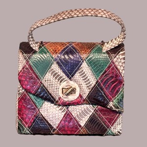 May include: A colorful, vintage handbag with a diamond pattern. The bag features a variety of colors including red, green, blue, and brown. It has a silver clasp and a braided handle. The bag is made of a textured material, possibly leather or snakeskin.