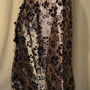 May include: A gold and black patterned blazer with a floral design. The blazer has a button closure and long sleeves.
