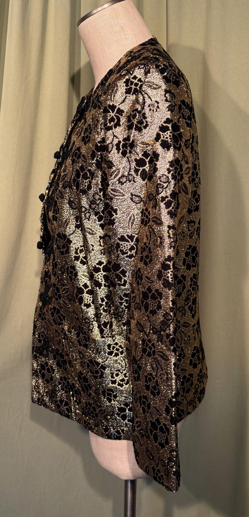 May include: A gold and black patterned blazer with a floral design. The blazer has a button closure and long sleeves.