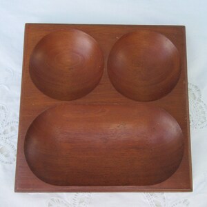 May include: A wooden serving tray with three separate compartments. The tray is made of dark brown wood and has a smooth, polished finish.