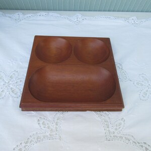 May include: A wooden serving tray with three separate compartments. The tray is made of dark brown wood and has a smooth, polished finish.