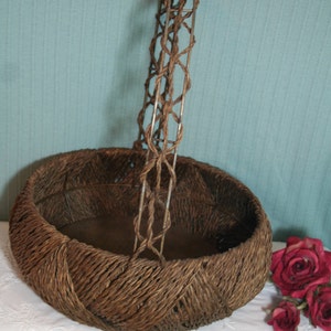 May include: A brown wicker basket with a woven handle. The basket is sitting on a white lace tablecloth.