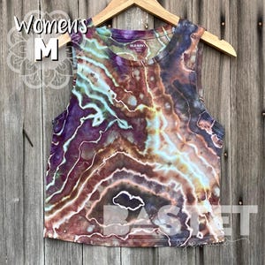 May include: A tie-dye tank top in shades of brown, purple, and blue. The tank top has a relaxed fit and a scoop neck. The tank top is made of a soft, comfortable fabric.