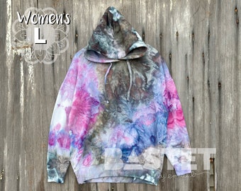 May include: A tie-dye hoodie in shades of pink, blue, and gray. The hoodie has a drawstring hood and a relaxed fit. The text "Women's L" is visible in the top left corner of the image.