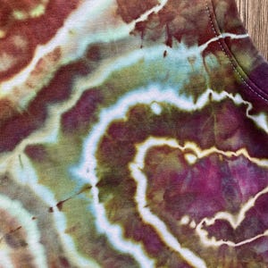 May include: Close-up of a tie-dye fabric with swirls of brown, green, and purple.