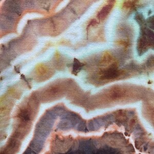 May include: Abstract tie-dye pattern in shades of brown, beige, and blue. The fabric has a swirling, marbled effect.