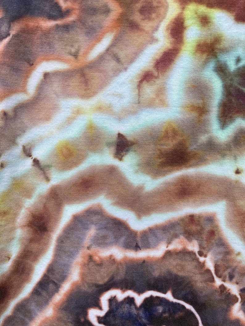May include: Abstract tie-dye pattern in shades of brown, beige, and blue. The fabric has a swirling, marbled effect.