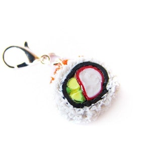 May include: A white, red, and green sushi roll charm with a silver lobster claw clasp. The sushi roll is made of polymer clay and is a realistic representation of a California roll.