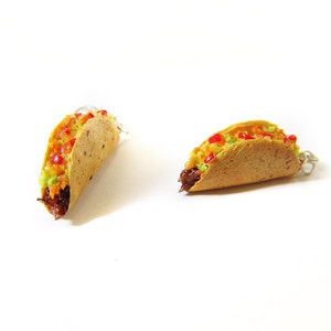 K&ouml;nnte beinhalten: Zwei Miniatur-Taco-Ohrringe aus Polymer Clay. Die Tacos sind gef&uuml;llt mit braunem Fleisch, gr&uuml;nem Guacamole und roter Salsa. Die Ohrringe sind an silbernen Ohrhaken befestigt.