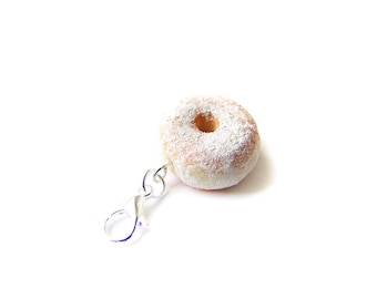 Könnte beinhalten: Ein kleiner, weißer, mit Puderzucker bestreuter Donut-Anhänger mit einem silbernen Verschluss. Der Donut ist etwa so groß wie eine 20-Cent-Münze.