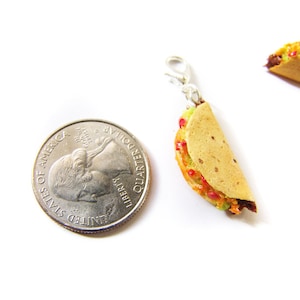 K&ouml;nnte beinhalten: Ein Miniatur-Taco-Anh&auml;nger mit einem goldfarbenen Verschluss. Der Taco ist mit roten und gr&uuml;nen Zutaten gef&uuml;llt und etwa so gro&szlig; wie eine US-amerikanische 25-Cent-M&uuml;nze.