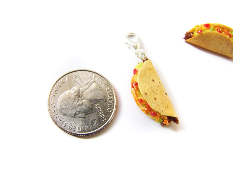 K&ouml;nnte beinhalten: Ein Miniatur-Taco-Anh&auml;nger mit einem goldfarbenen Verschluss. Der Taco ist mit roten und gr&uuml;nen Zutaten gef&uuml;llt und etwa so gro&szlig; wie eine US-amerikanische 25-Cent-M&uuml;nze.