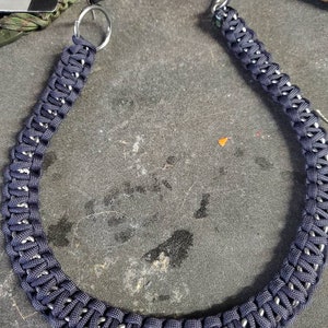 May include: A dark blue paracord keychain with a silver metal ring. The keychain is woven in a complex pattern and is approximately 30 inches long.