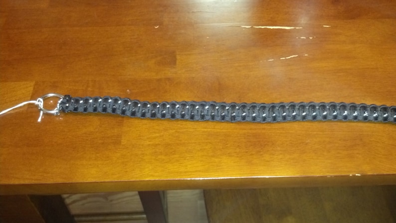 May include: A black paracord bracelet with a silver metal clasp.