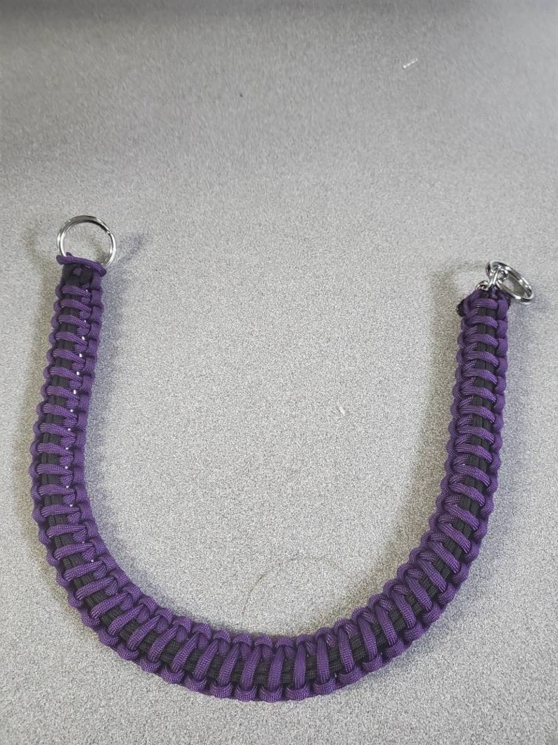 May include: A purple and black paracord keychain with silver metal rings.