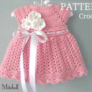 May include: A crochet baby dress pattern in pink with white flowers and a white ribbon. The pattern is called "PATTERN Crochet".