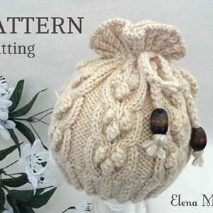 May include: A cream-colored knitted drawstring bag with a cable knit pattern and wooden beads. The bag is made with a chunky yarn and has a gathered top.