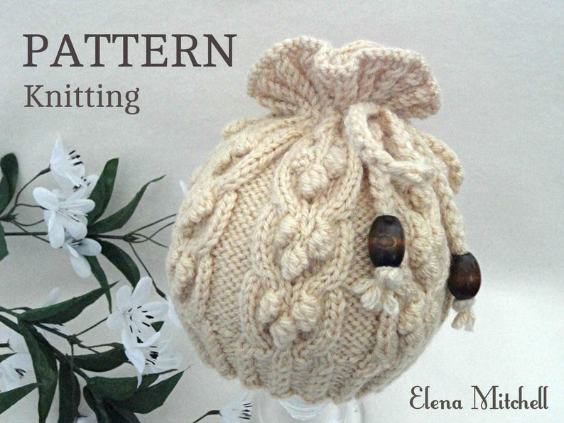 May include: A cream-colored knitted drawstring bag with a cable knit pattern and wooden beads. The bag is made with a chunky yarn and has a gathered top.