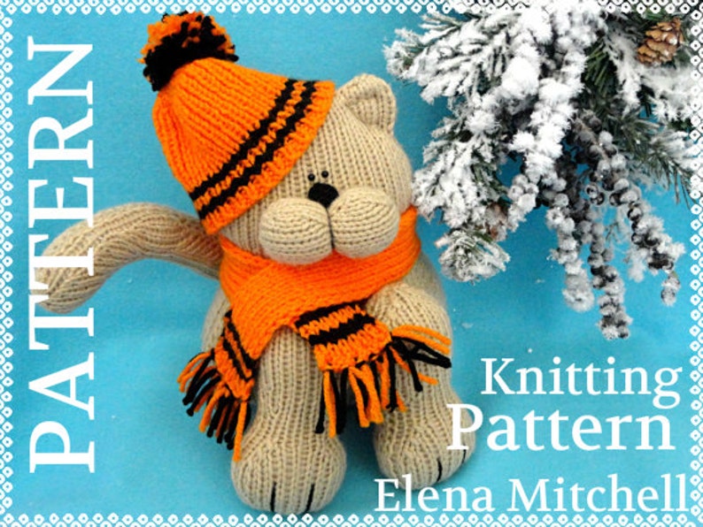 Peut inclure: Patron de tricot pour un ours en peluche beige portant un bonnet et une &eacute;charpe ray&eacute;s orange et noir. L'ours est assis sur un fond bleu avec une branche de pin enneig&eacute;e en arri&egrave;re-plan. Le texte "Knitting Pattern Elena Mitchell" est visible sur l'image.