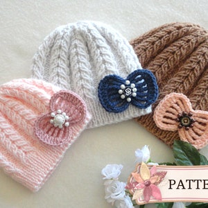 May include: Three knitted baby hats in pink, white, and brown, each adorned with a decorative bow. The pink hat has a light pink bow, the white hat has a navy blue bow, and the brown hat has a peach bow. The hats are arranged on a white surface.