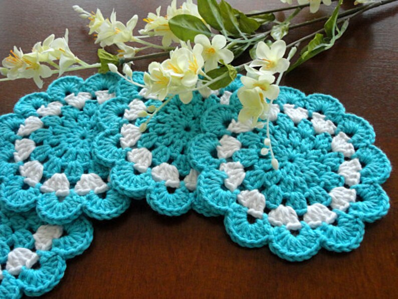 May include: Four crocheted turquoise and white coasters with a scalloped edge.