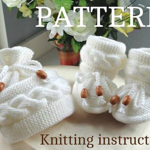 May include: White knitted baby booties and a matching hat with a cable knit pattern and wooden buttons. The pattern is titled "PATTERN" and the knitting instructions are below.