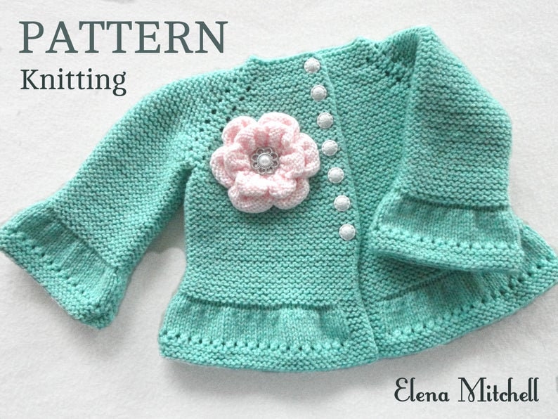 May include: A knitted baby cardigan in a light green colour with a pink flower embellishment and white buttons. The cardigan has a ruffled hem and sleeves. The text "PATTERN Knitting" is visible at the top of the image.