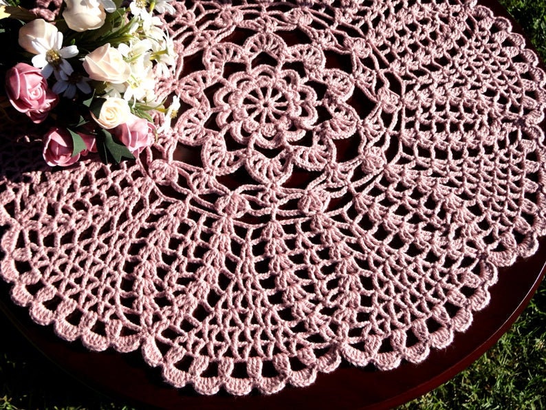 Peut inclure: Une dentelle crochet&eacute;e rose d&eacute;licate avec un motif circulaire. La dentelle a un motif floral central et un bord festonn&eacute;.