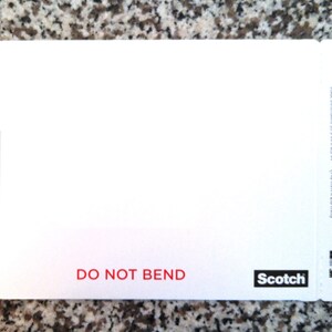 May include: White self-sealing envelope with a Scotch logo and the text "Photo/Document Mailer" and "DO NOT BEND". The envelope measures 5.75 x 8.5 inches (146 mm x 215 mm).