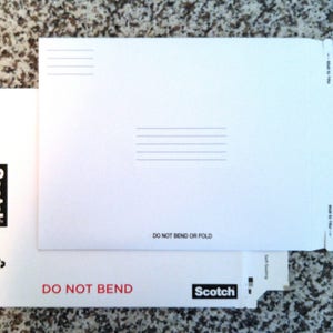 May include: White envelope with a Scotch logo and the text "Do Not Bend or Fold". The envelope is made for photo or document mailing.