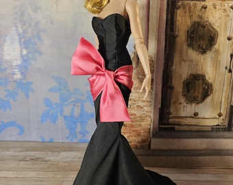 May include: A black strapless gown with a large pink bow at the waist. The gown has a fitted bodice and a flowing skirt.