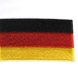 May include: A rectangular embroidered patch featuring the horizontal tricolor flag of Germany. The design consists of three equal horizontal bands in black at the top, red in the middle, and gold at the bottom, with a stitched border edge.