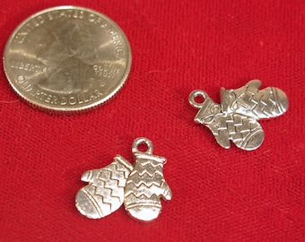 May include: Two silver charm pendants shaped like mittens with a textured design. The charms are about the size of a US quarter.