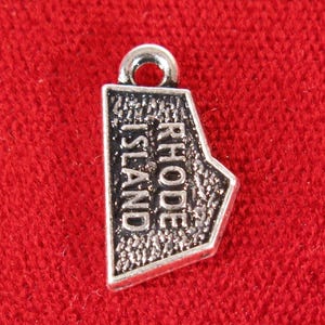 May include: Silver charm shaped like the state of Rhode Island with the words "Rhode Island" inscribed on it.