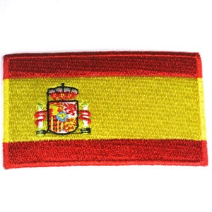May include: An embroidered patch of the Spanish flag. The flag is red, yellow, and red with the Spanish coat of arms in the center.