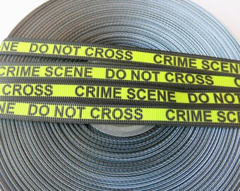 May include: A roll of black and gray ribbon with the words "CRIME SCENE DO NOT CROSS" printed in black on a bright yellow background. The ribbon is tightly wound, showing the texture of the material.
