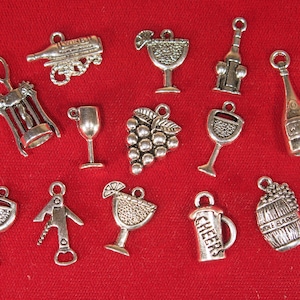 May include: A collection of 13 silver charm pendants with wine and cocktail themes. The charms include a wine bottle, a corkscrew, a wine glass, a grape cluster, a margarita glass, a beer mug, and a wine barrel.