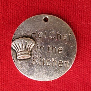 May include: Silver charm with a chef's hat and the text "Hot Chef in the Kitchen".