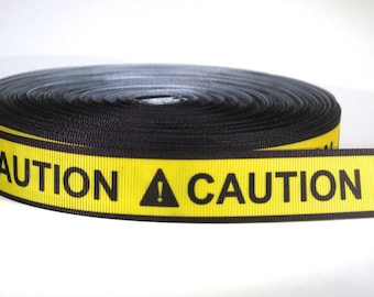 May include: A roll of black and yellow caution tape with the word "CAUTION" printed in black letters and a black triangle with an exclamation point inside.